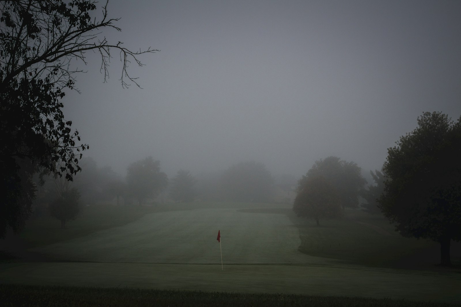 Foggy golf course with red flag